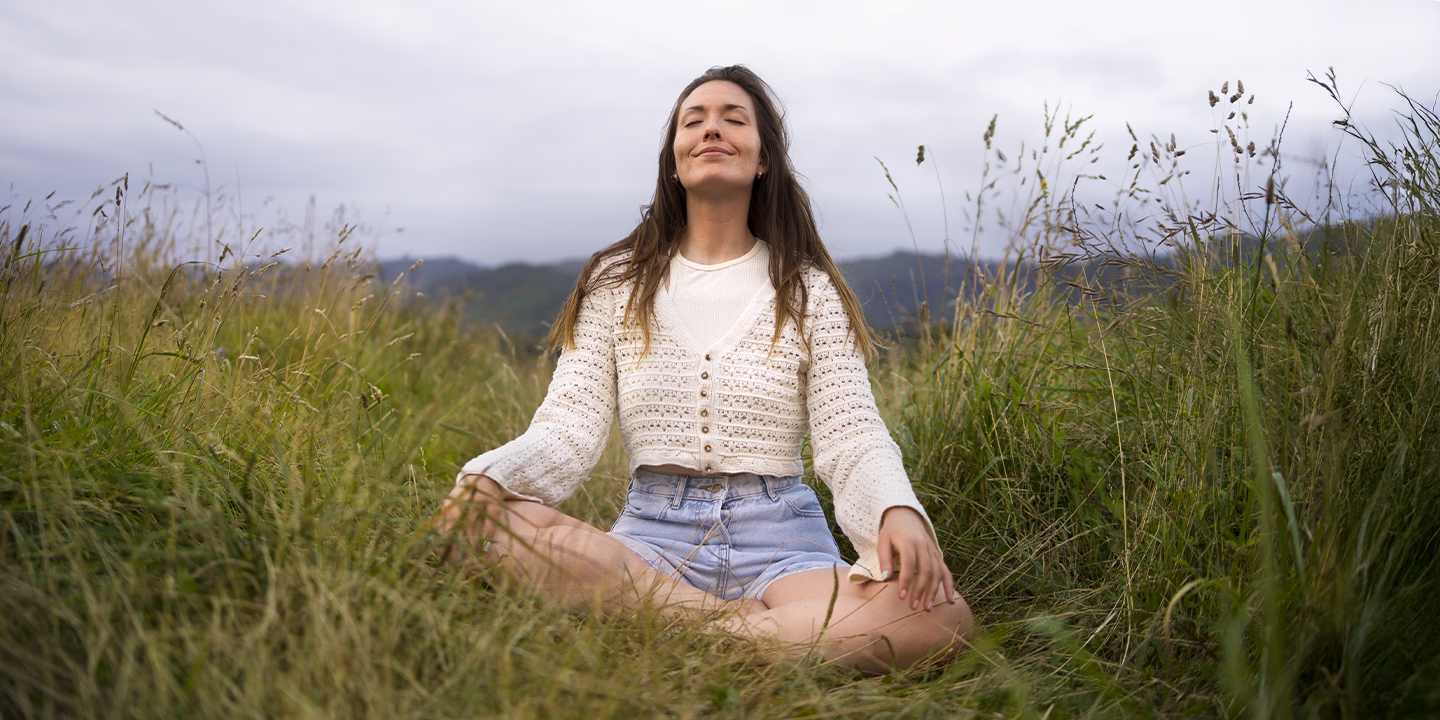 Femme méditant dans la nature, symbole de transformation et de renouveau associé à la vibration du nombre 13 en numérologie.