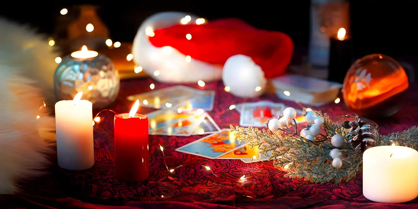Table de Noël illuminée avec des cartes de tarot, des bougies et des décorations hivernales, symbolisant la guidance spirituelle et la magie du tirage de cartes pendant les fêtes.