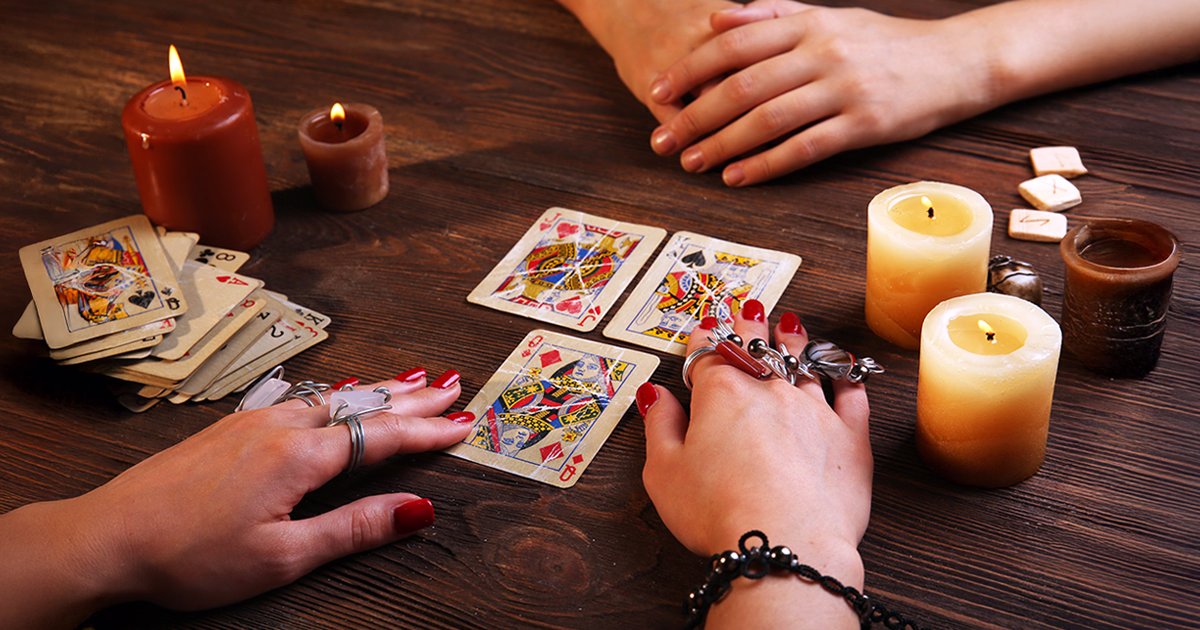 Kartenlegung mit einem 32-Karten-Spiel auf einem Tisch mit Kerzen, Symbol für die Deutung und Bedeutung der Karten im Wahrsagen.