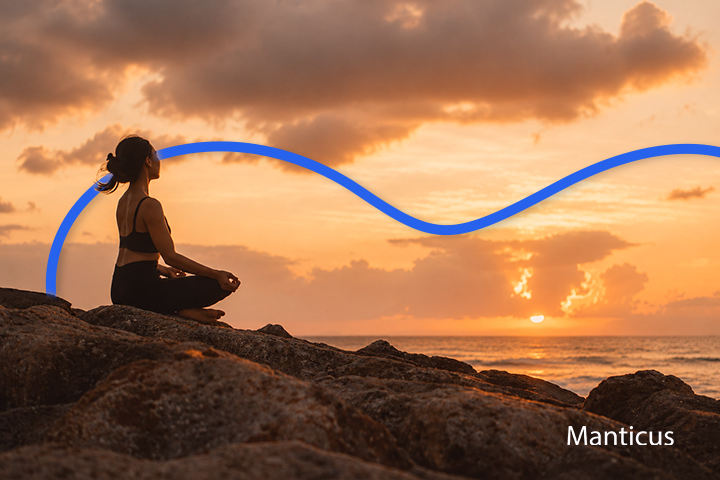 Frau meditiert bei Sonnenuntergang am Meer und entwickelt Achtsamkeit, innere Ruhe sowie geistige Klarheit durch regelmäßige Meditation.