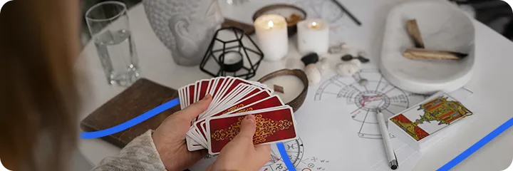 Hand, die ein Tarotkartendeck hält, umgeben von Kerzen, Räucherwerk und spirituellen Symbolen – Darstellung einer weihnachtlichen Kartenlegung.