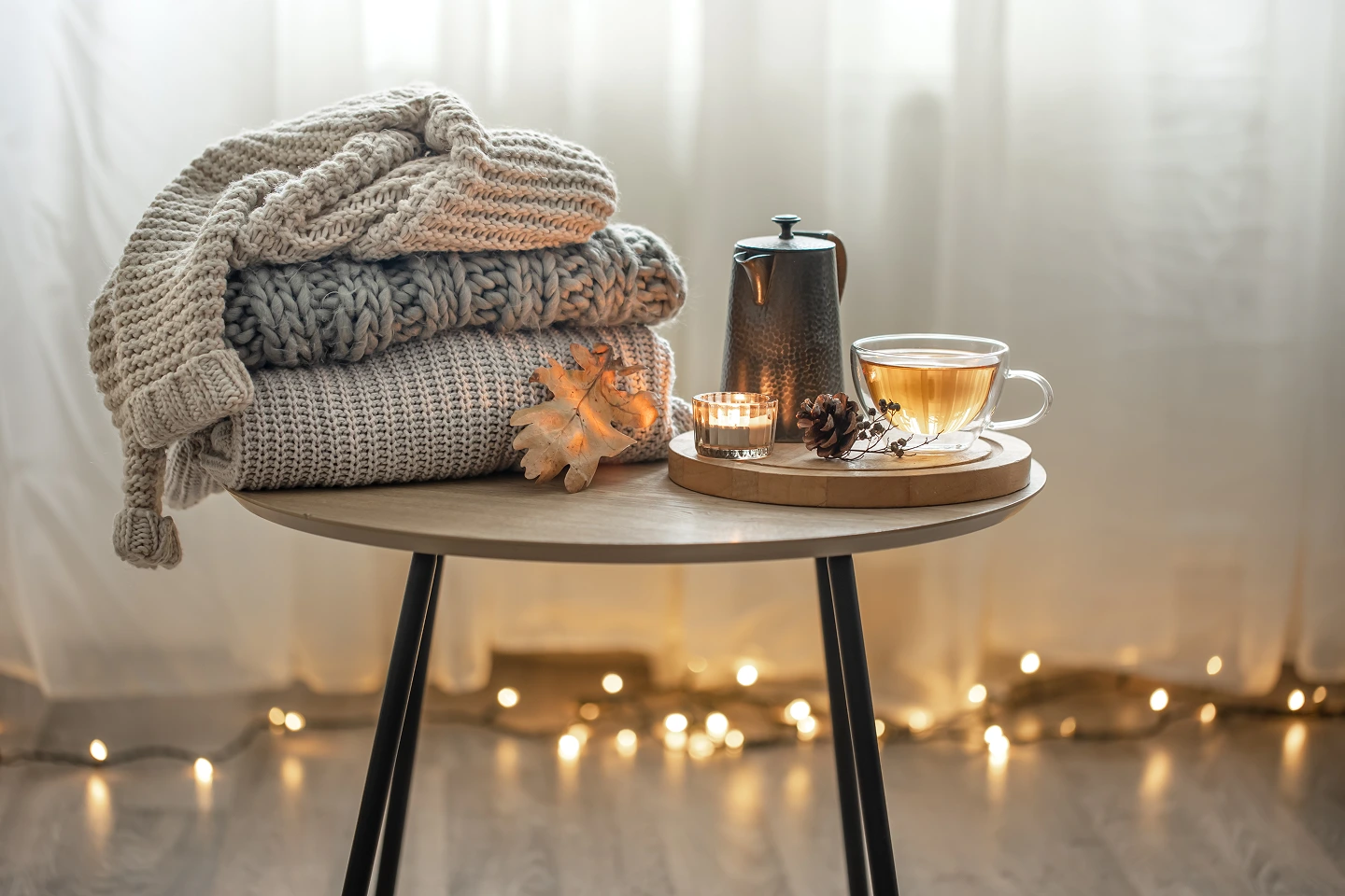 Table d’hiver avec couvertures en laine, thé chaud, bougie et théière, évoquant un rituel de chaleur, apaisement et transition spirituelle.