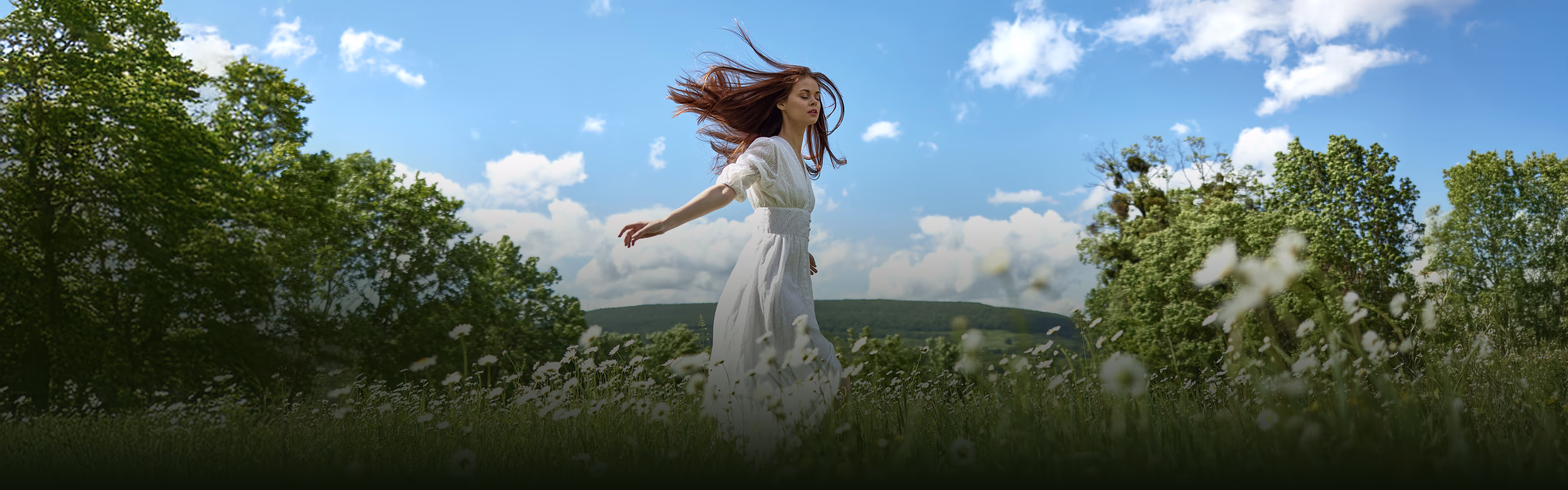 Eine Frau tanzt auf einem Frühlingsfeld unter blauem, sonnigem Himmel